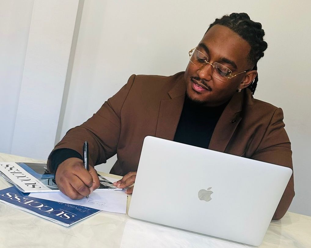 Carlito Henry au travail, écrivant sur une table avec laptop